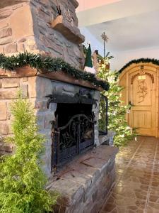 a stone fireplace with christmas trees and a door at Willa Kosówka - Apartamenty i pokoje in Zakopane