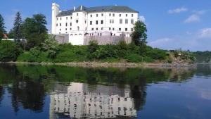 ein großes weißes Schloss auf einer Insel im Wasser in der Unterkunft Apartmány U Orlického jezera - Kamenice in Klučenice