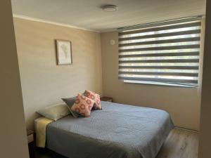 sypialnia z łóżkiem z poduszkami i oknem w obiekcie Departamento nuevo con perfecta ubicación w mieście Osorno