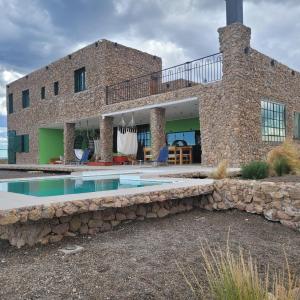 a stone house with a swimming pool in front of it at Casona Islas Blancas in Camarones