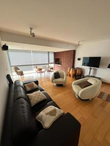 a living room with a black leather couch and chairs at Penthouse Villa brava in Punta del Este