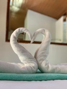 two towel swans forming a heart on a bed at Casa Amarela Cipó Suítes e Cipó Kombi VIP 600m centro Serra do Cipó in Santana do Riacho