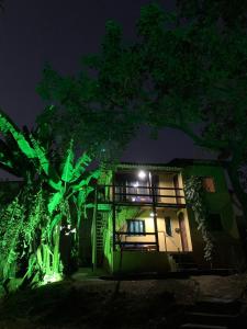 una casa iluminada por la noche con luces verdes en Casa Amarela Cipó Suítes e Cipó Kombi VIP 600m centro Serra do Cipó, en Santana do Riacho
