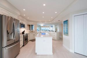 uma grande cozinha com armários brancos e um frigorífico em Steps to Beach & Pool - Resort Amenities Galore! em Clearwater Beach