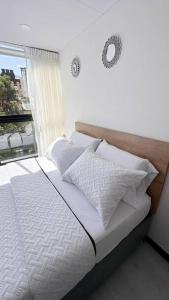 een slaapkamer met een wit bed en een raam bij Movistar arena 302 in Bogota