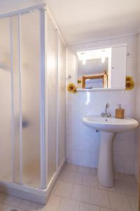 a white bathroom with a shower and a sink at Gavalochori Stone House in Gavalochori