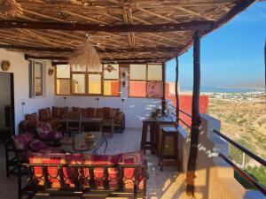 - une terrasse couverte avec des chaises et des tables et une vue sur l'océan dans l'établissement Red Carpet Surf Camp, à Tamraght Ouzdar