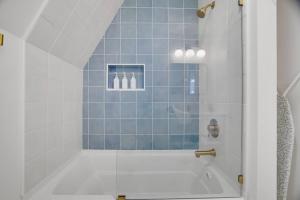a bathroom with a tub with blue tiles at Modern A-frame in woods with Sauna, HotTub, Privacy in Albrightsville +37 photos