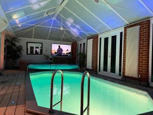 una piscina con techo y TV. en Broadway Pool House with Sauna & Jacuzzi en Herne Bay