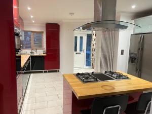 a kitchen with red cabinets and a stove top at Broadway Pool House with Sauna & Jacuzzi in Herne Bay