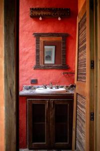 uma casa de banho com um lavatório e um espelho numa parede vermelha em Finca La Colina em Armênia