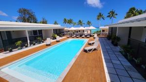 a swimming pool with lounge chairs and a house at Resort Tava'e in Amuri