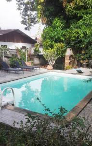 una piscina en un patio con sillas y árboles en Charmant Lodge tout confort en Matoury