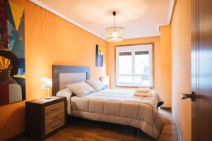a bedroom with orange walls and a bed and a window at Casa Losada in Monforte de Lemos