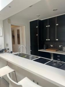 uma cozinha com armários pretos e um lavatório em Chart Cottage em Stanmore