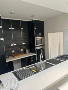 uma cozinha com armários pretos e um lavatório em Chart Cottage em Stanmore