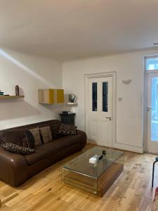 a living room with a brown couch and a glass table at Chart Cottage in Stanmore