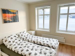 um quarto com uma cama e duas janelas em Spacious apartment with 3 bedrooms next to amazing nature em Tromsø