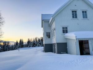 ein weißes Haus im Schnee mit Bäumen in der Unterkunft Spacious apartment with 3 bedrooms next to amazing nature in Tromsø