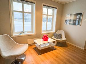 uma sala de estar com uma mesa, cadeiras e janelas em Spacious apartment with 3 bedrooms next to amazing nature em Tromsø