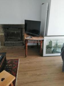 a living room with a tv and a table with a television at Maison face aux îles de Melon, Molène et Ouessant 6P in Porspoder