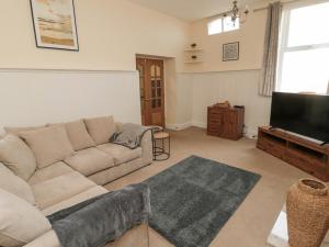 a living room with a couch and a flat screen tv at Courtyard Cottage in Alnwick