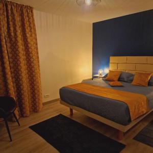 um quarto com uma cama grande e uma parede azul em les chambres de Sandra em Volognat