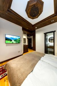 a bedroom with a large bed with a tv on the wall at Hotel - Kulla e Zenel Beut in Peje