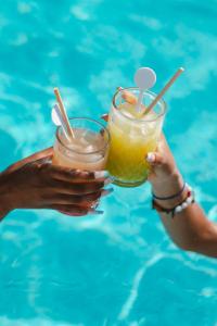 zwei Personen, die vor einem Pool Getränke halten in der Unterkunft Hotel LLITERAS in Cala Ratjada