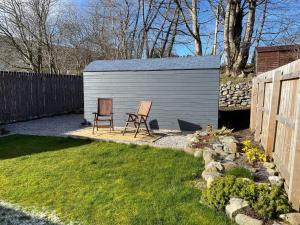 a shed with two chairs in a yard at Hideaway Pod near Loch Ness for a tranquil retreat in Lewiston