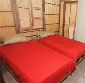 two beds in a room with red sheets at El Viejo Moi Hospedaje & Restaurante in Cabo de la Vela