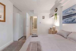 a white bedroom with a large bed in it at Spacious and modern London duplex apartment with garden in London