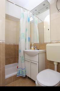 a bathroom with a sink and a toilet and a mirror at Apartments Aurora Adriatica in Brist +18 photos