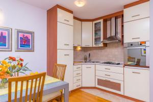 een keuken met witte kasten en een tafel en een eetkamer bij Apartment Galeria in Omiš