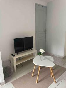 sala de estar con TV y mesa en Petit studio aux portes du beaujolais, en Saint-Germain-Nuelles