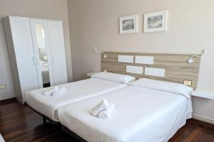 - 2 lits blancs dans une chambre avec un miroir dans l'établissement Apartamentos Turísticos Guillermo, à Palas de Rei