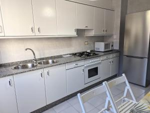 La cuisine est équipée de placards blancs, d'un évier et d'un réfrigérateur. dans l'établissement Apartamentos Turísticos Guillermo, à Palas de Rei