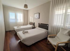una habitación de hotel con 2 camas y una silla en Apartamentos Turísticos Guillermo en Palas de Rei 