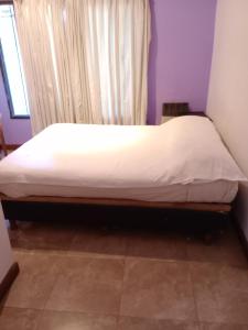 Una cama en una habitación con una sábana blanca. en Santa Elena Hostal, en Luján 4 fotos más