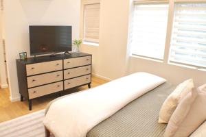 a bedroom with a tv and a dresser with a bed at Centrally located modern townhome free parking in Chattanooga