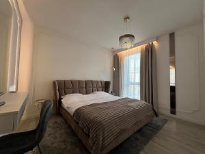 a bedroom with a bed and a desk and a window at Harmony Property WIN HERASTRAU in Bucharest