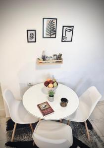 a white table and chairs with a bowl of fruit on it at S&A Modern Apartment in Igoumenitsa