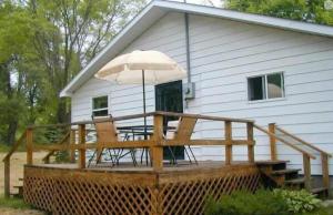 a deck with an umbrella and chairs and a table at Pet Friendly Cottage in Thompsonville