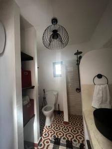 a bathroom with a toilet and a chandelier at Le Cabaoui in Poponguine