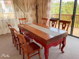 a dining room table with chairs and a large window at Maungaraki View in Lower Hutt