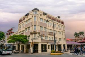 un edificio en la esquina de una calle con un autobús en Hotel Cityzen Guayaquil en Guayaquil