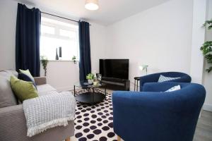 a living room with blue chairs and a tv at Tram Lane by Tŷ SA in Merthyr Tydfil