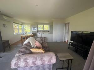 una sala de estar con un sofá con un gato tirado en él en Rotorua Lakes House en Rotorua