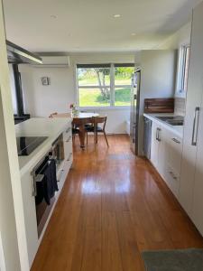 a kitchen with white cabinets and a wooden floor at Rotorua Lakes House in Rotorua