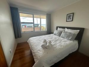 a bedroom with a bed with white sheets and a window at Rotorua Lakes House in Rotorua